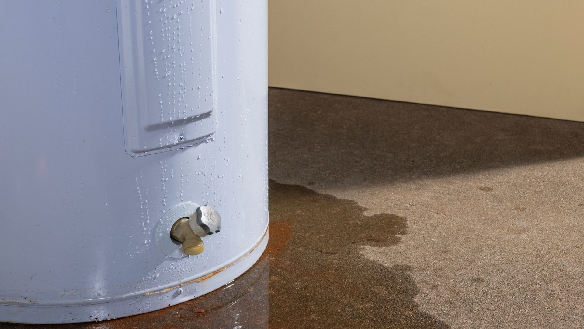 Leaking water heater with condensation and water puddle on floor