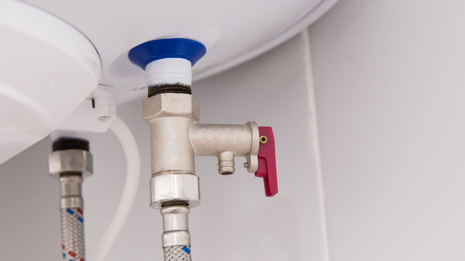 Water heater valve with blue and red handle connected to flexible pipe
