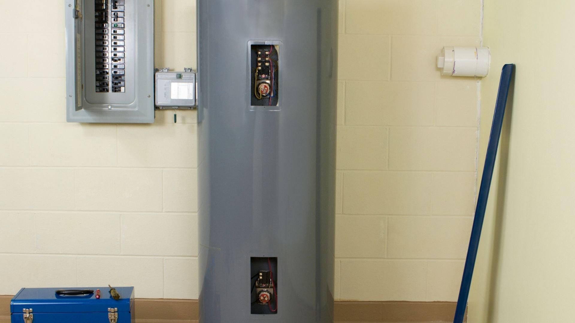 Large gray water heater next to electrical panel and blue toolbox