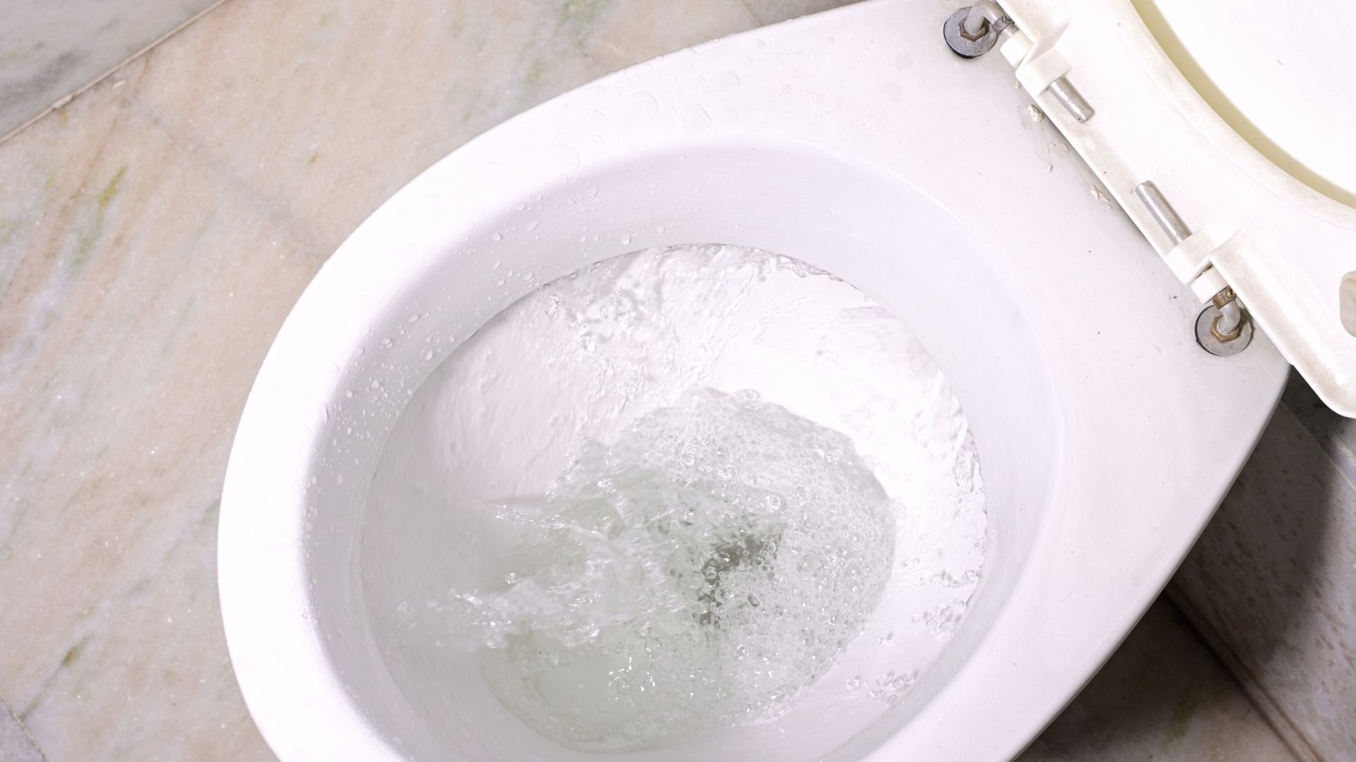 White toilet bowl with flushing water and bubbles