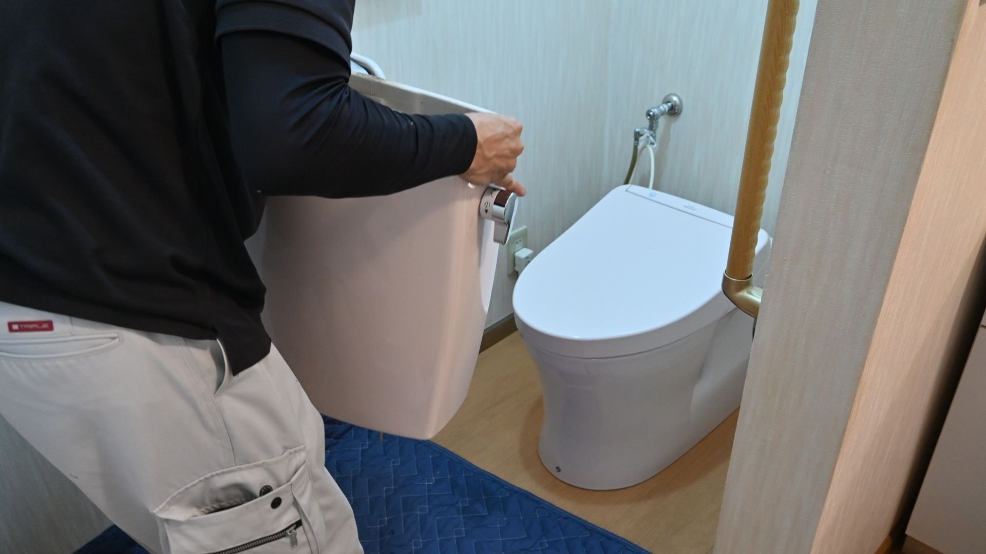 Person adjusting or using a modern white toilet in a bathroom
