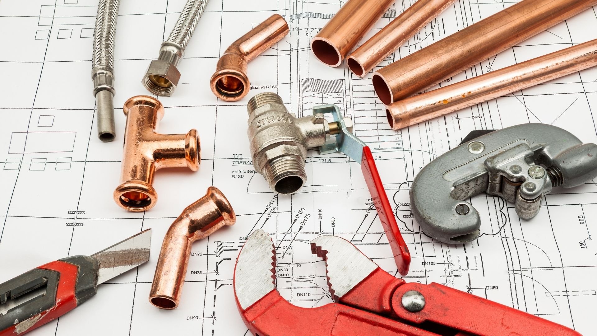 Plumbing tools and copper pipes on technical blueprint for installation