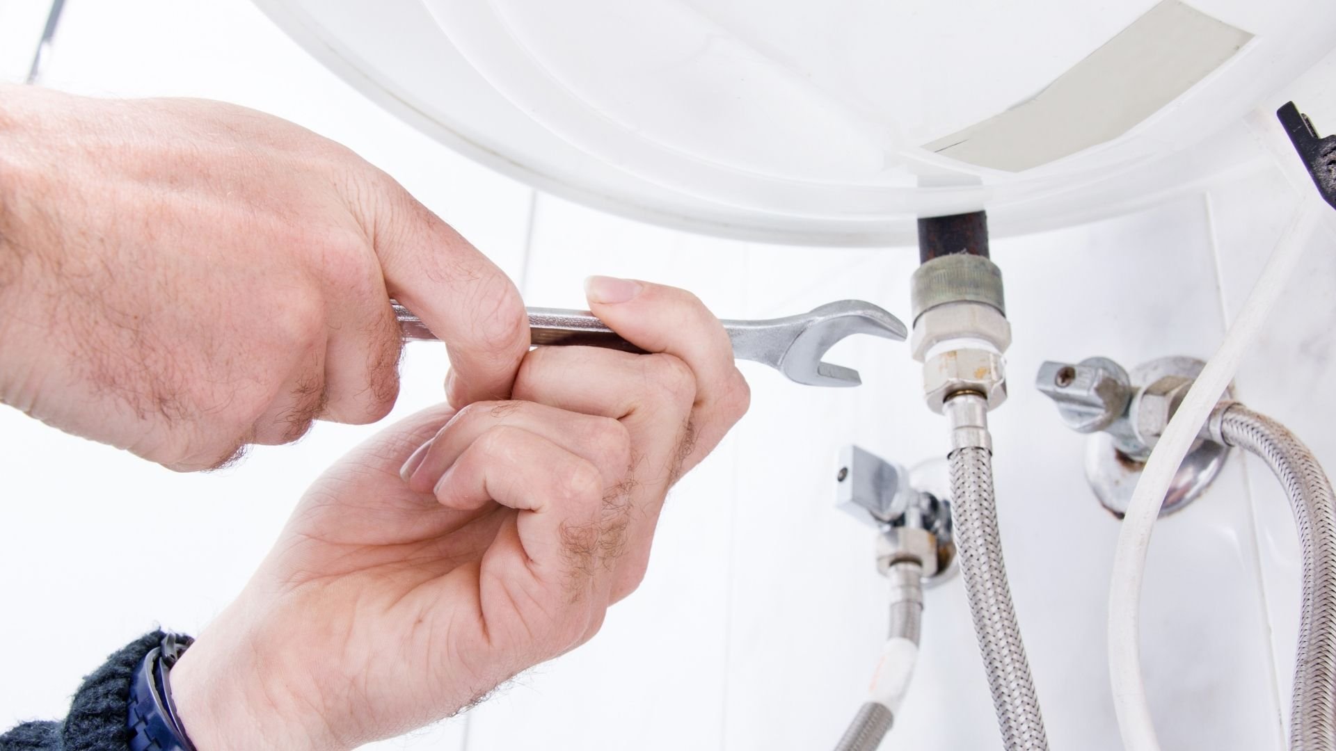 Hands using a wrench to repair plumbing pipes and connections